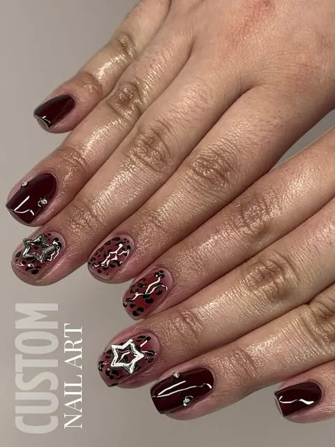 Burgundy manicure with custom nail art, done at Artistic Trendz