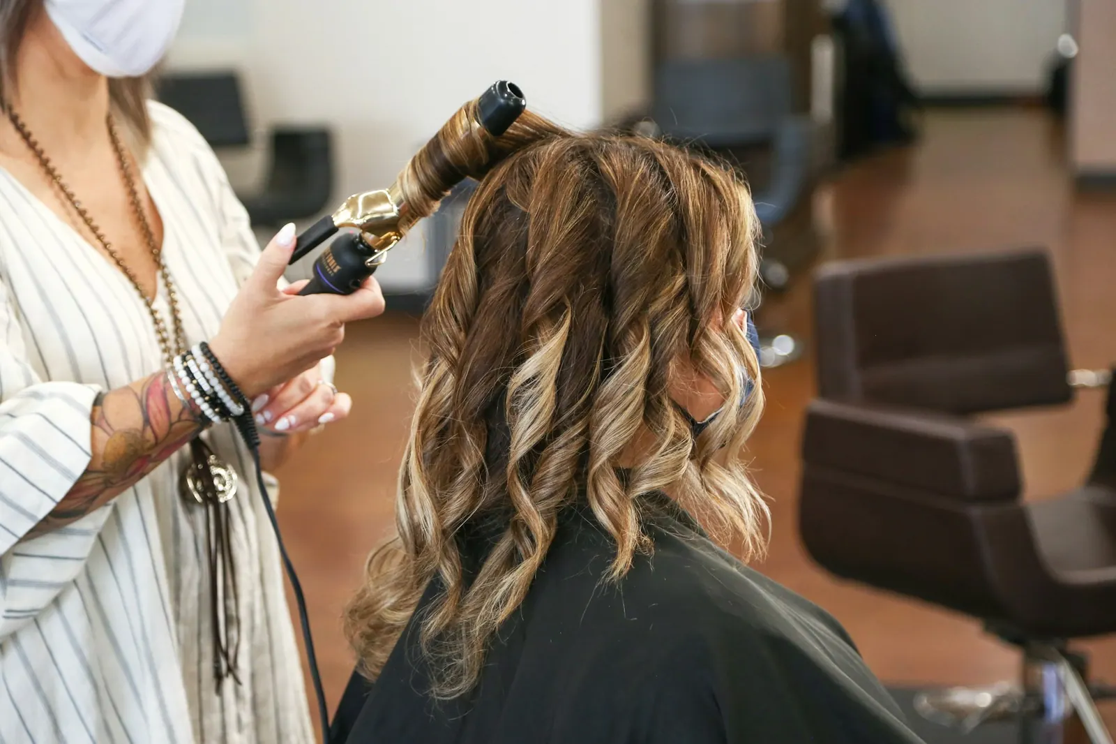 Stylist curling a client's hair with a curling iron